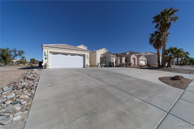 mediterranean / spanish-style house with an attached garage, a tile roof, concrete driveway, and stucco siding