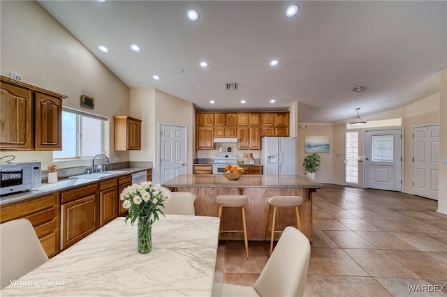 kitchen featuring under cabinet range hood, white appliances, a sink, visible vents, and a center island