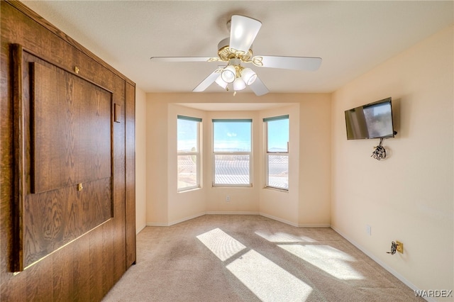 unfurnished bedroom with light carpet, ceiling fan, and baseboards