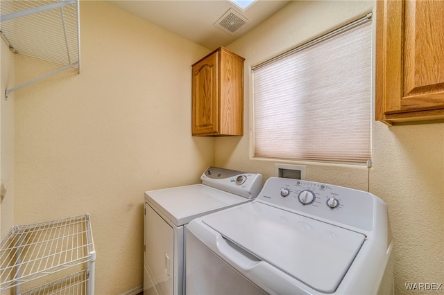 clothes washing area with cabinet space, a textured wall, visible vents, and independent washer and dryer