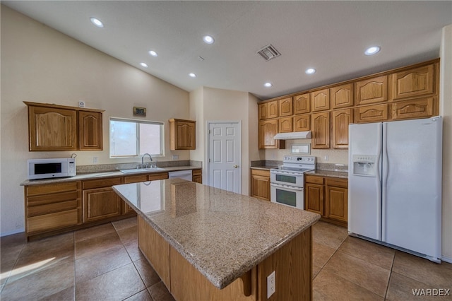 kitchen with white appliances, a sink, visible vents, a center island, and tile patterned floors