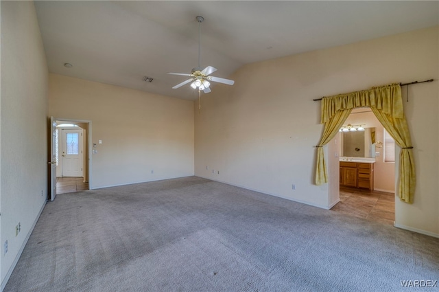 empty room featuring light carpet, high vaulted ceiling, visible vents, and a ceiling fan