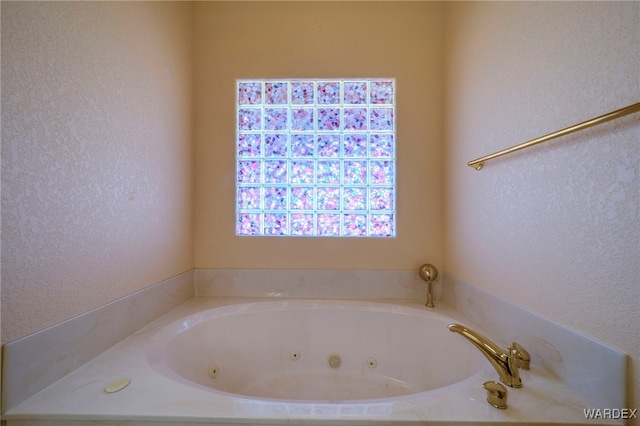 full bath with a textured wall and a jetted tub