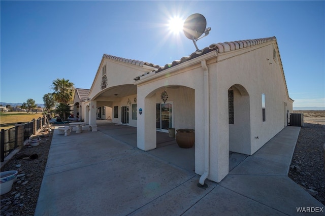 rear view of house featuring a patio, central air condition unit, stucco siding, fence, and a tiled roof