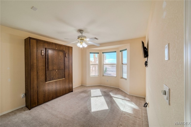 unfurnished bedroom featuring a ceiling fan, light colored carpet, and baseboards