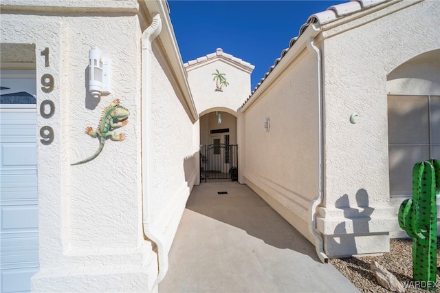 view of exterior entry featuring an attached garage and stucco siding