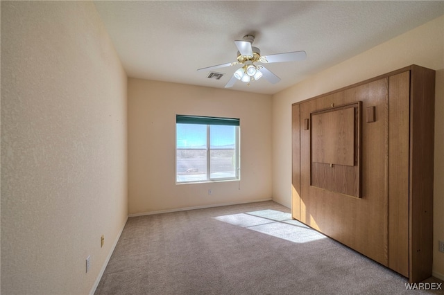 unfurnished bedroom with ceiling fan, visible vents, baseboards, and light colored carpet