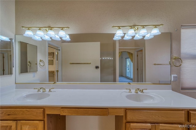 bathroom with double vanity, a textured ceiling, and a sink