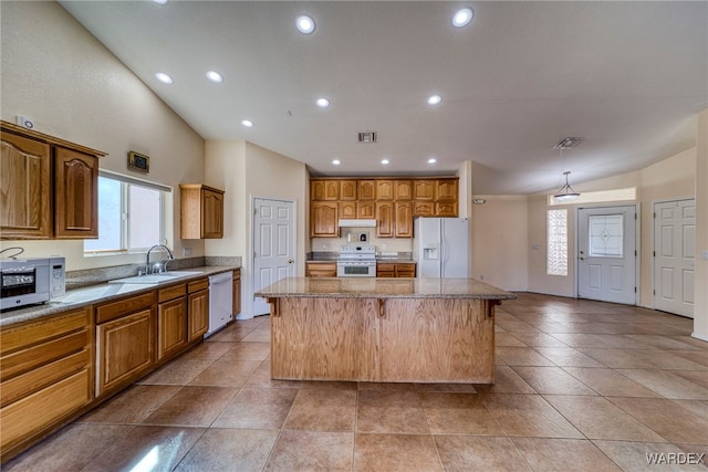 kitchen with under cabinet range hood, white appliances, a sink, visible vents, and a center island