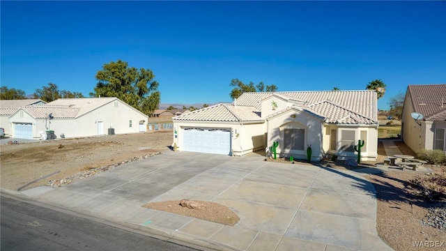 mediterranean / spanish-style house featuring a garage, concrete driveway, a tiled roof, and stucco siding