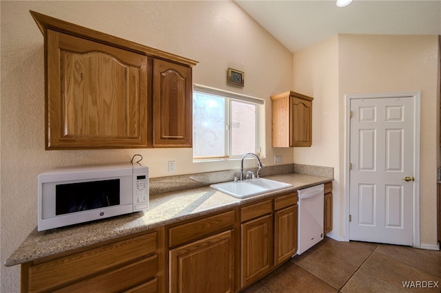 kitchen featuring brown cabinets, white appliances, a sink, and tile patterned floors