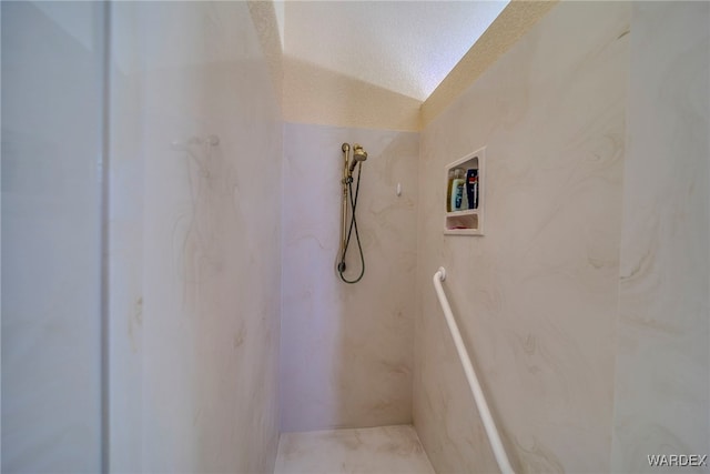 full bath featuring a textured ceiling, vaulted ceiling, and a marble finish shower