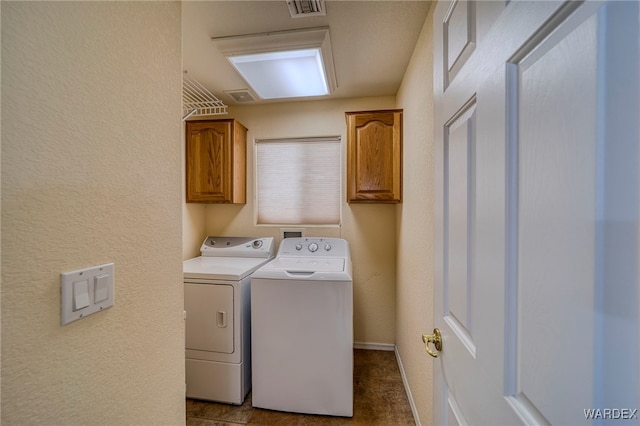 laundry area with a textured wall, visible vents, baseboards, cabinet space, and washing machine and clothes dryer