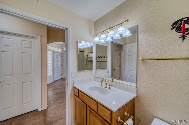 bathroom with a textured wall, vanity, and tile patterned floors