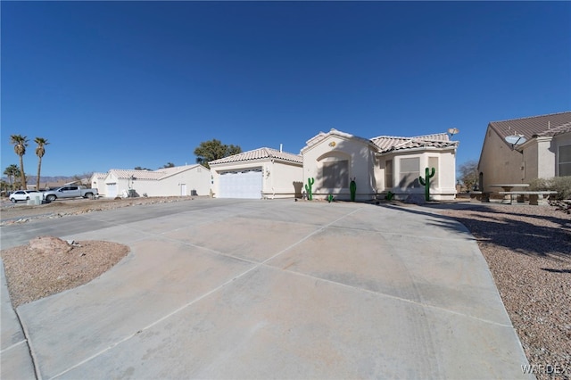 mediterranean / spanish-style house featuring driveway, stucco siding, an attached garage, and a tiled roof