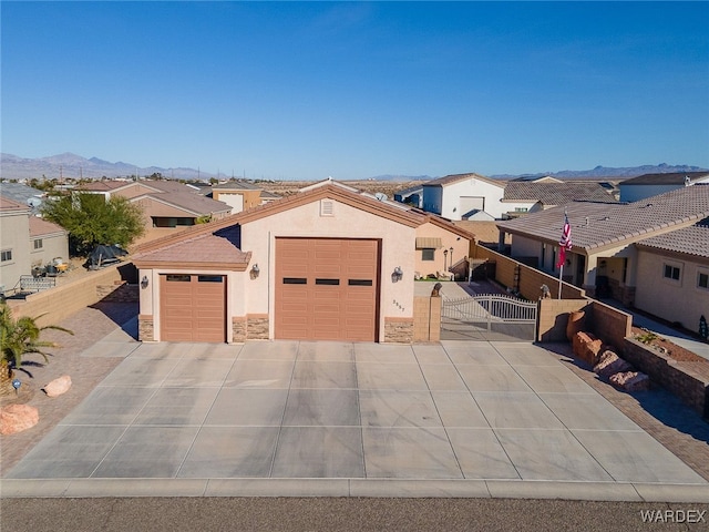 mediterranean / spanish home featuring an attached garage, a mountain view, stone siding, a residential view, and stucco siding