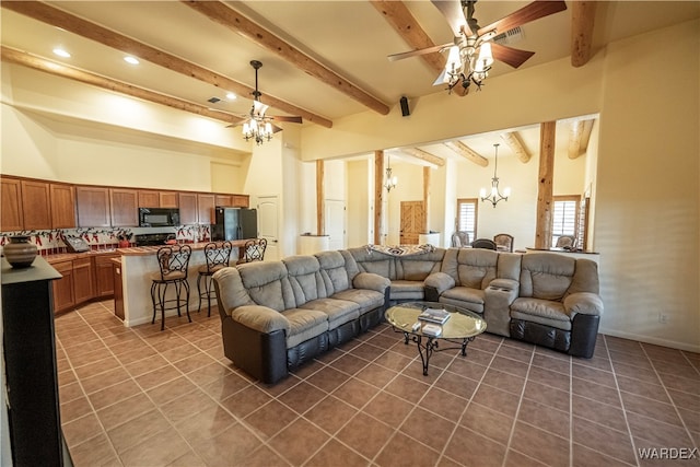 living area with ceiling fan with notable chandelier, dark tile patterned flooring, visible vents, and beam ceiling