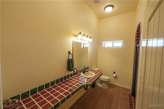 bathroom featuring visible vents, toilet, a sink, baseboards, and tile patterned floors