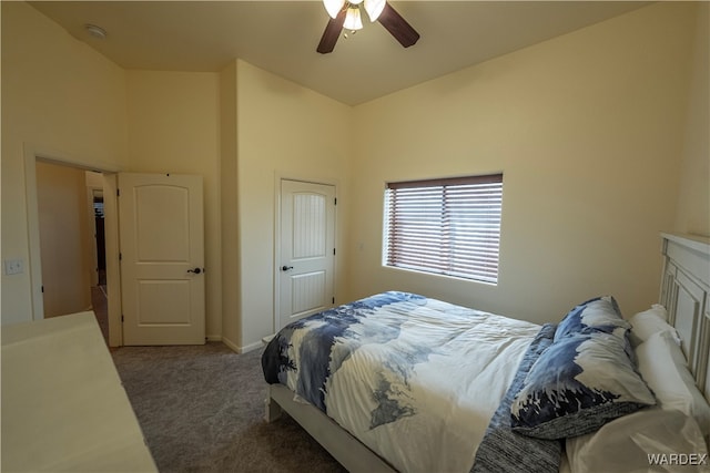 bedroom with a high ceiling, dark colored carpet, and a ceiling fan