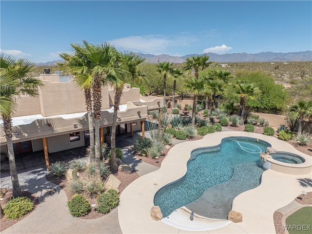 view of pool featuring a patio area, a pool with connected hot tub, fence, and a mountain view