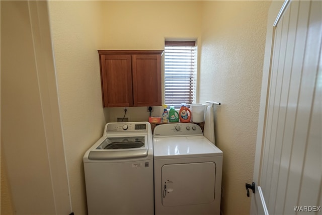 laundry room featuring a textured wall, independent washer and dryer, and cabinet space