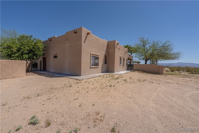 view of property exterior with a mountain view, fence, and stucco siding