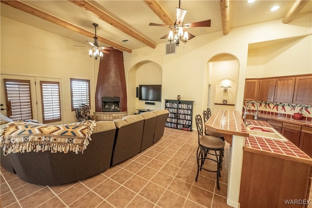 living area with ceiling fan, visible vents, beamed ceiling, and tile patterned floors