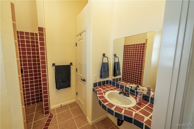 bathroom featuring tile patterned flooring, a sink, and baseboards