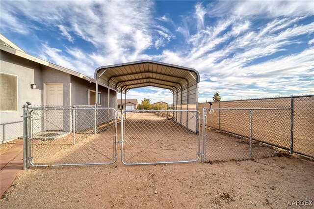 view of yard with a detached carport, driveway, fence, and a gate