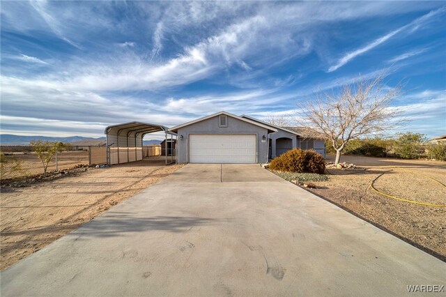 ranch-style house featuring a carport, stucco siding, a mountain view, a garage, and driveway