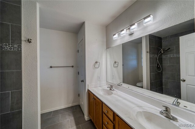 full bathroom featuring double vanity, toilet, a sink, and tile patterned floors