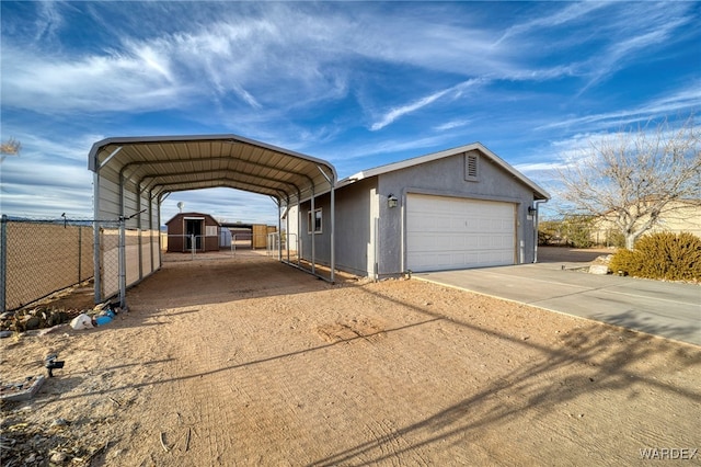 view of front of house featuring a garage, stucco siding, fence, and an outdoor structure