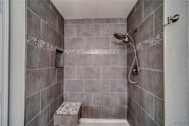 full bath with a textured ceiling and a tile shower