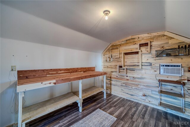 unfurnished bedroom featuring dark wood finished floors, vaulted ceiling, and wooden walls