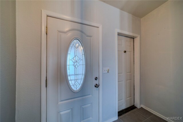 foyer featuring dark tile patterned floors and baseboards