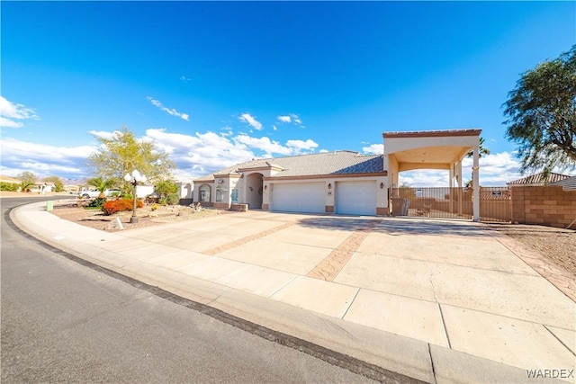 view of front facade featuring driveway, an attached garage, a gate, fence, and stucco siding