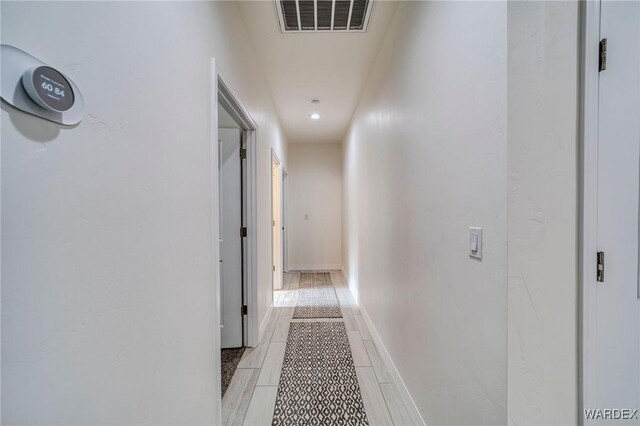 hallway featuring visible vents and baseboards