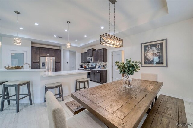 dining room featuring baseboards, a raised ceiling, and recessed lighting