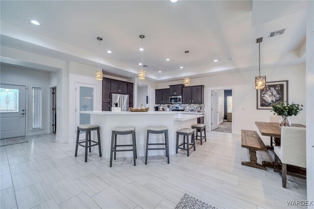 kitchen featuring dark brown cabinetry, appliances with stainless steel finishes, light countertops, and decorative light fixtures