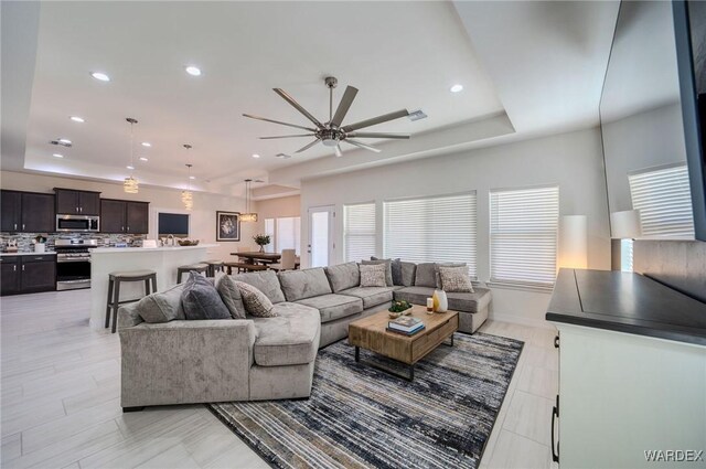 living room with ceiling fan, a raised ceiling, visible vents, and recessed lighting