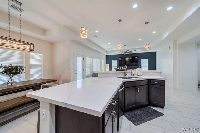 kitchen featuring a tray ceiling, open floor plan, a sink, and a center island with sink