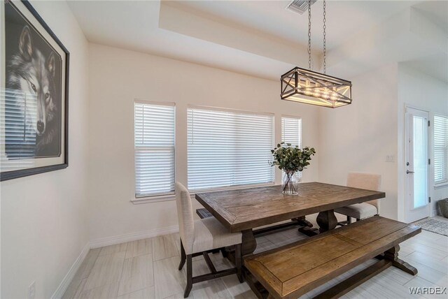 dining area with a raised ceiling, visible vents, and baseboards