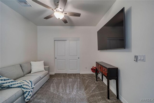 living room featuring dark colored carpet, visible vents, ceiling fan, and baseboards