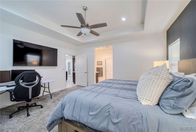 bedroom with baseboards, a ceiling fan, light colored carpet, ensuite bath, and a tray ceiling