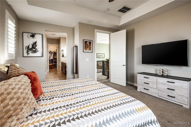 carpeted bedroom with baseboards, ensuite bathroom, and visible vents
