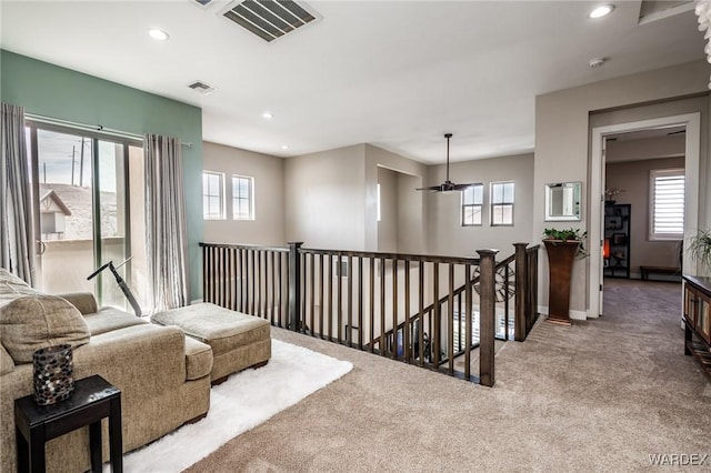 sitting room with carpet floors, recessed lighting, visible vents, and an upstairs landing
