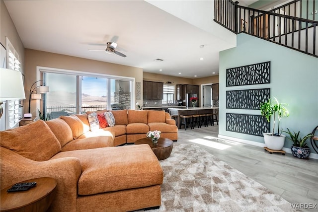 living room featuring light wood-style floors, baseboards, a ceiling fan, and recessed lighting