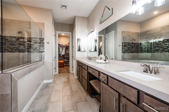 bathroom with a sink, tile patterned floors, baseboards, visible vents, and a stall shower