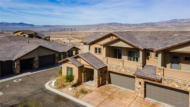 view of front of home featuring a garage, a mountain view, concrete driveway, and stone siding