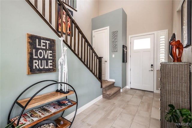 foyer with stairs, a high ceiling, and baseboards